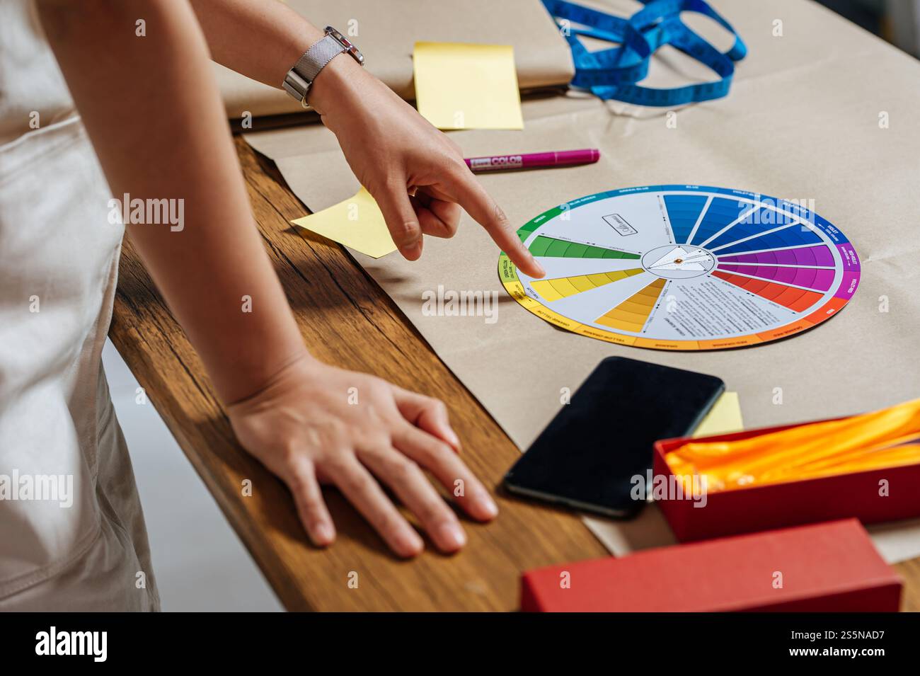 Gros plan main du concepteur masculin point sur la roue de couleurs sur la table tout en travaillant en studio Banque D'Images