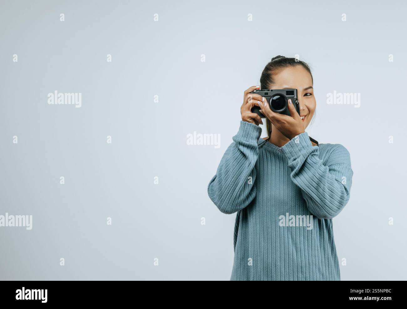 Portrait de femme asiatique portant des vêtements décontractés avec un grand sourire sur le visage, prenant des photos avec l'appareil photo. Fond isolé en studio avec espace vide. Banque D'Images