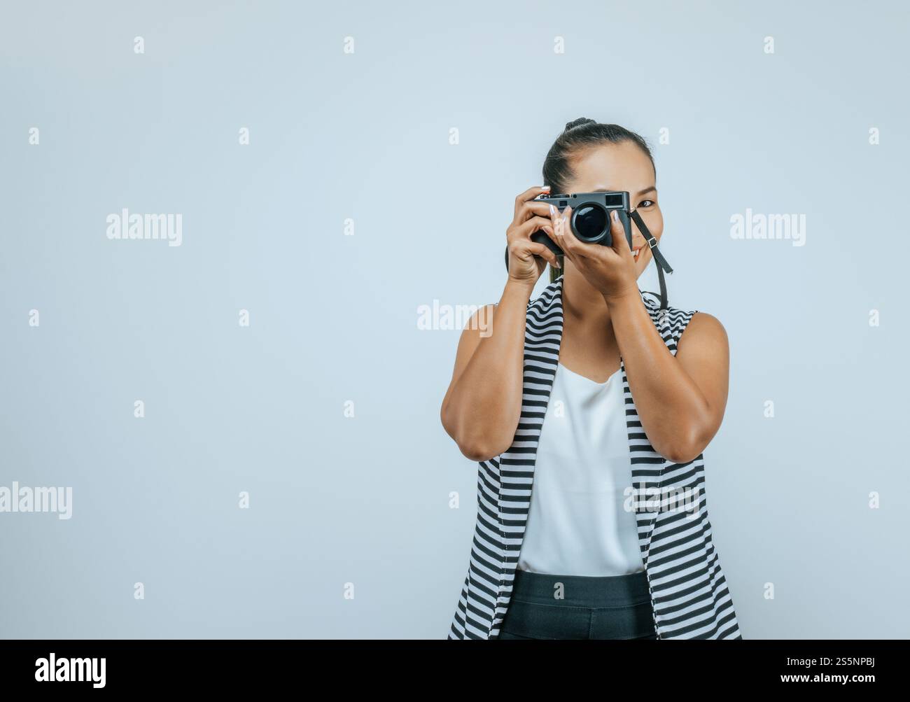 Portrait de femme asiatique portant des vêtements décontractés avec un grand sourire sur le visage, prenant des photos avec l'appareil photo. Fond isolé en studio avec espace vide. Banque D'Images