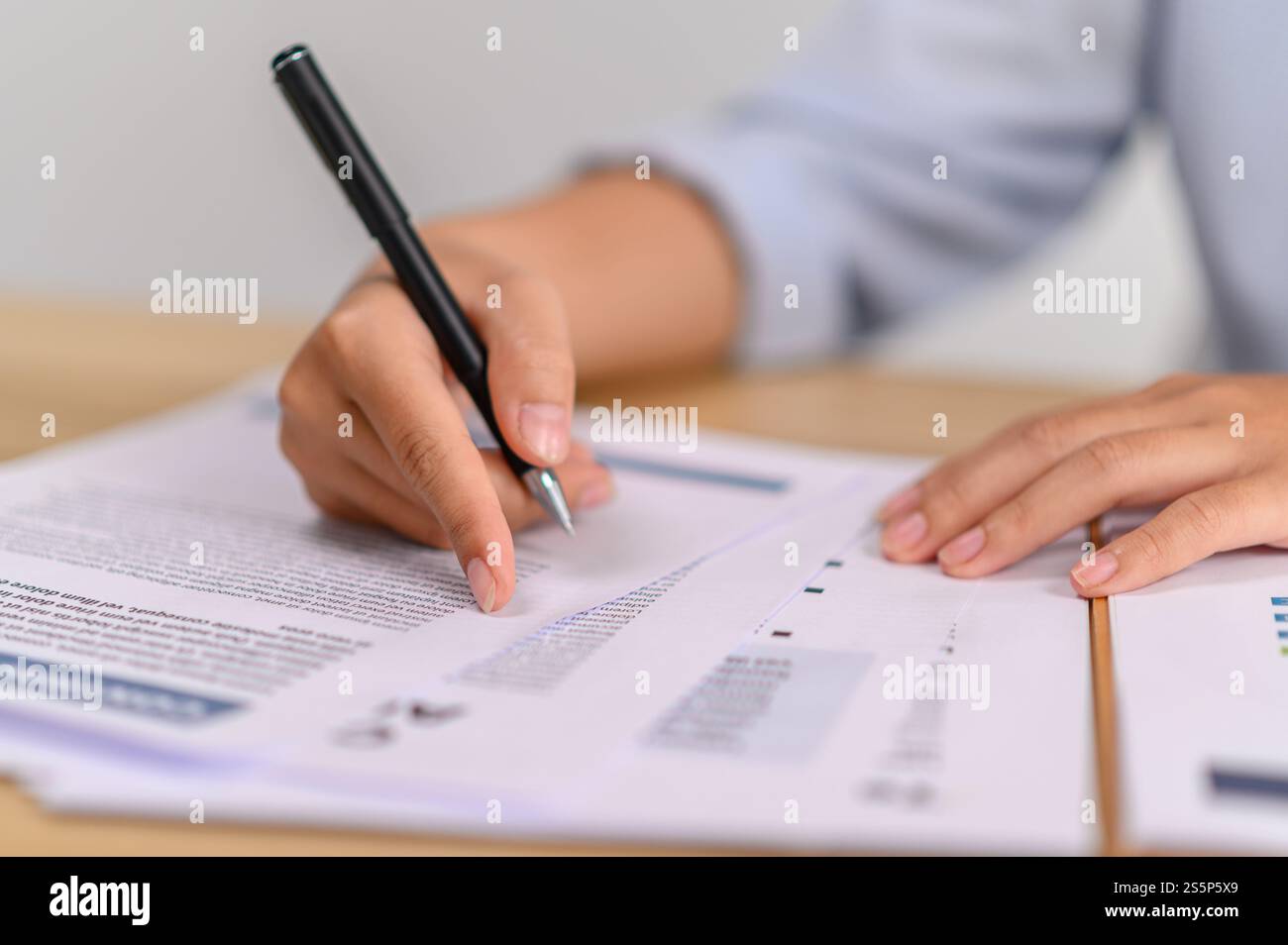 employé féminin tenant un stylo pour écrire des documents au bureau Banque D'Images