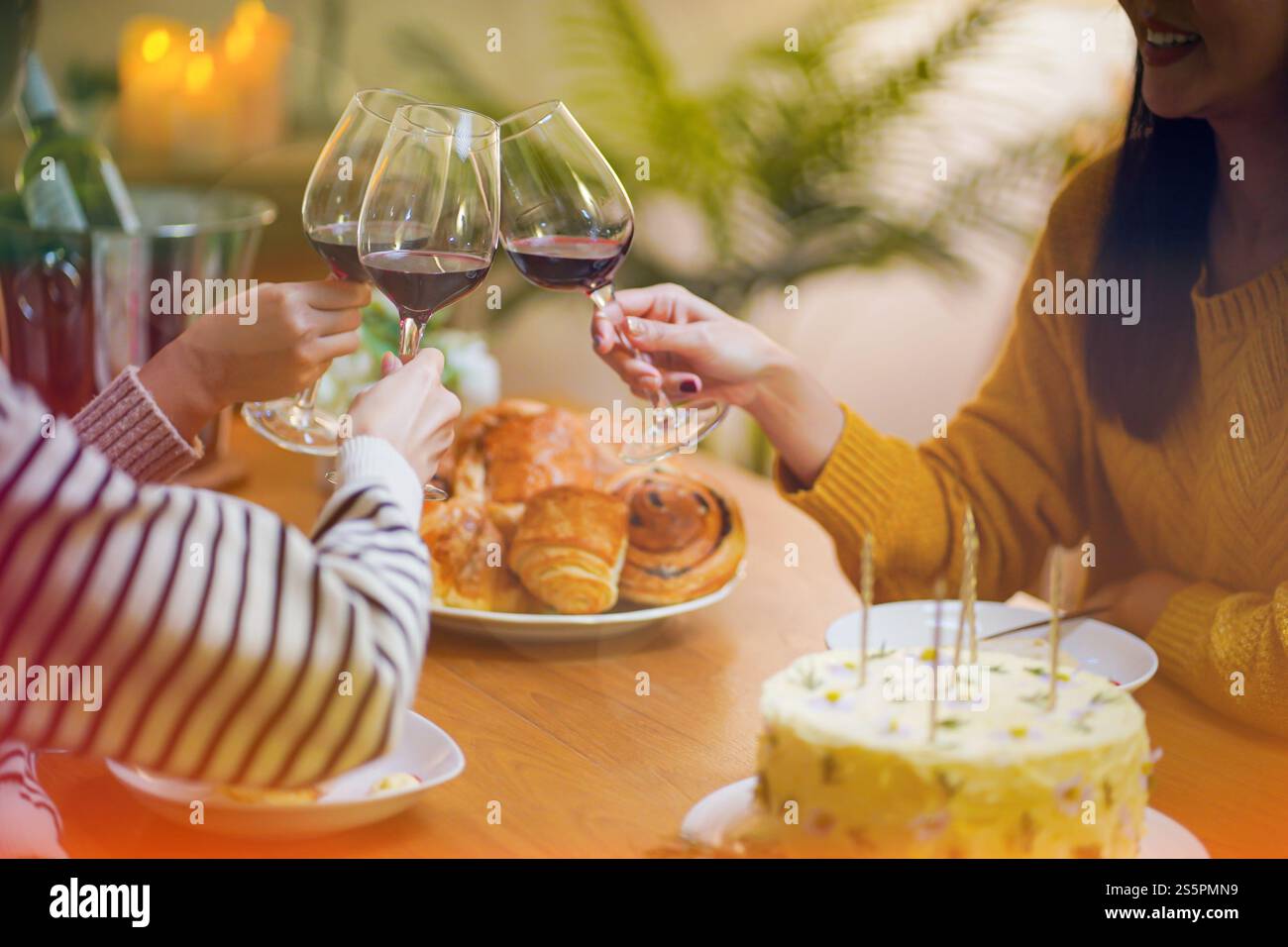 Amis joyeux appréciant la fête de vacances d'anniversaire à la maison. Amis asiatiques acclamant boire du vin rouge célébrant la fête du nouvel an Banque D'Images