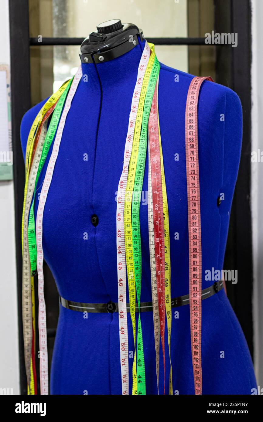 Un mannequin bleu vif de tailleur orné de rubans à mesurer colorés dans un studio de couture professionnel. Parfait pour les thèmes liés à la couture, fash Banque D'Images