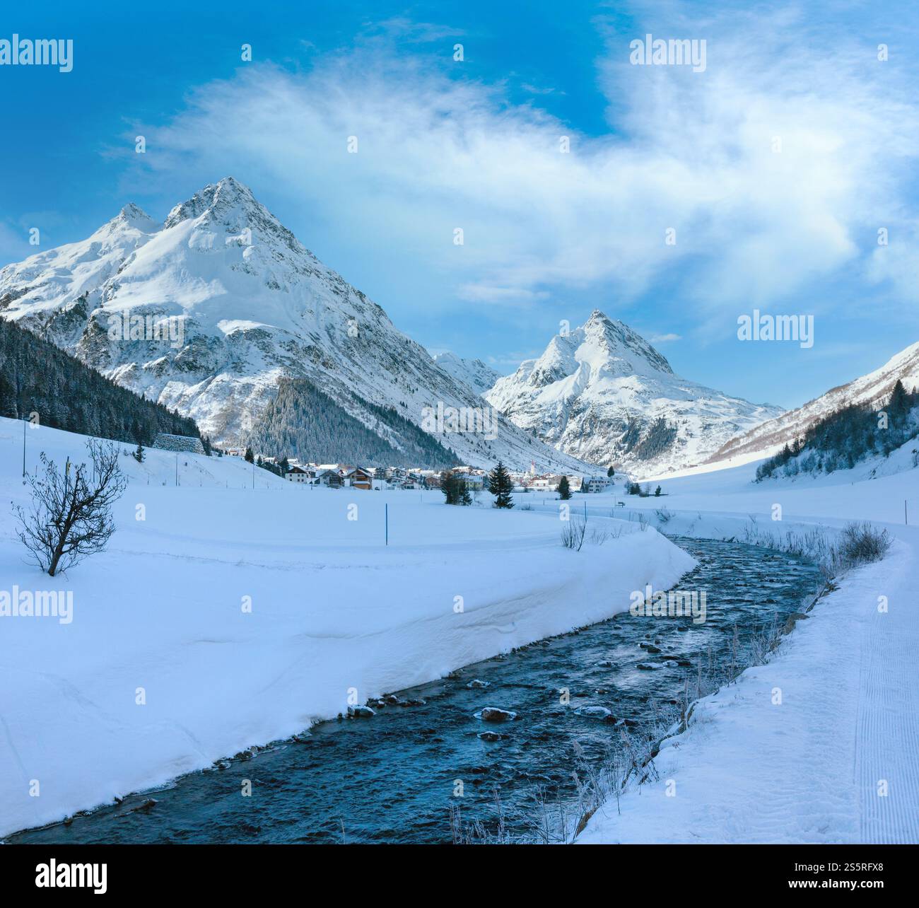 Vue sur les cours d'eau de montagne en hiver et village dans la vallée (Autriche). Banque D'Images