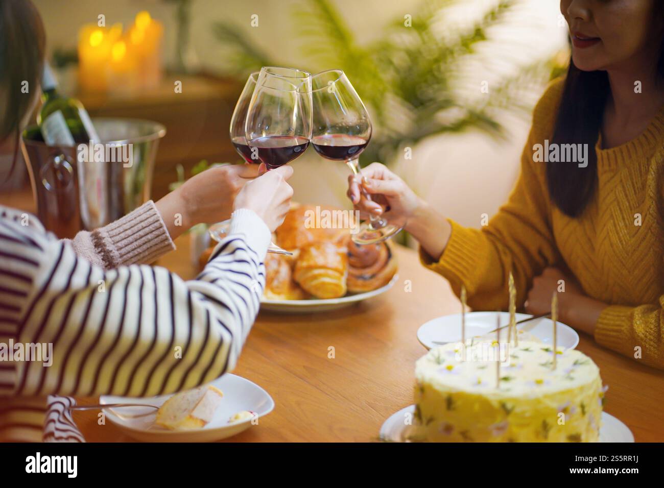 Amis joyeux appréciant la fête d'anniversaire à la maison. Amis asiatiques acclamant boire du vin rouge pour célébrer Noël ou la fête du nouvel an. Banque D'Images