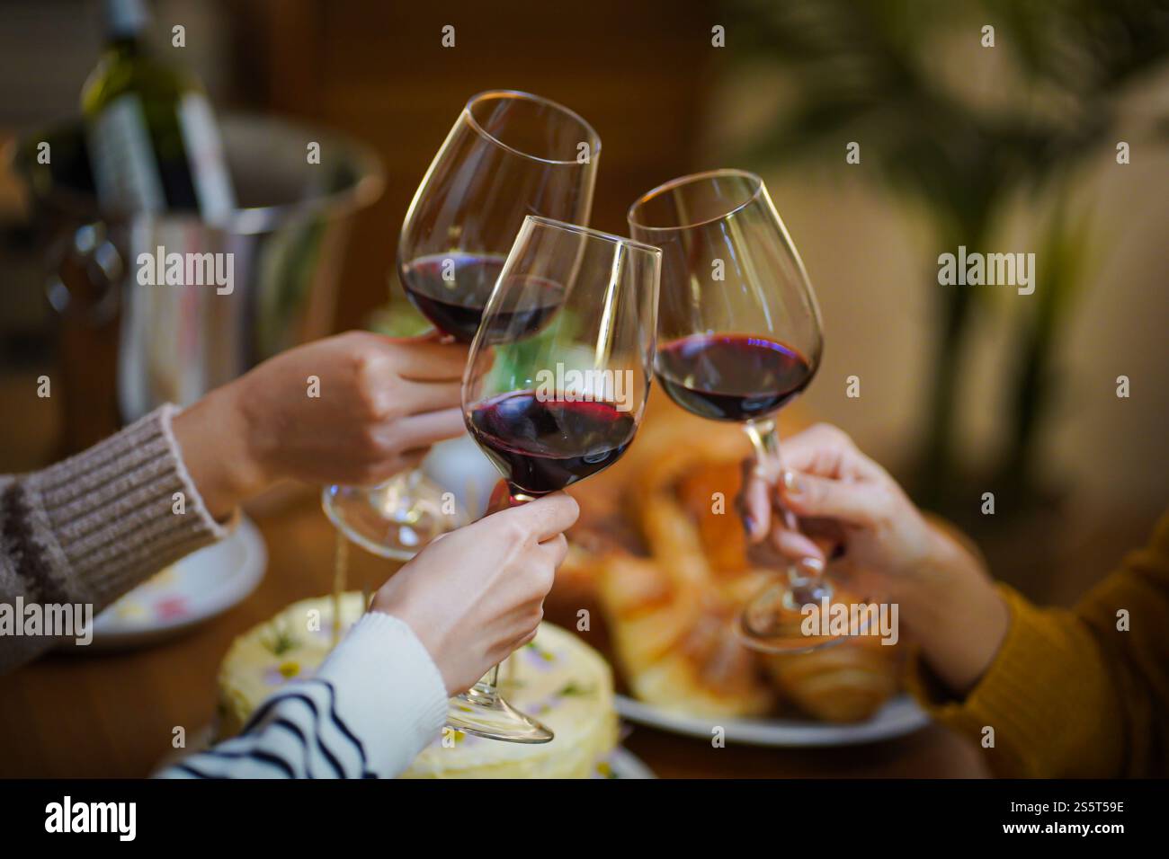 Amis joyeux appréciant la fête d'anniversaire à la maison. Amis asiatiques acclamant boire du vin rouge pour célébrer Noël ou la fête du nouvel an. Banque D'Images