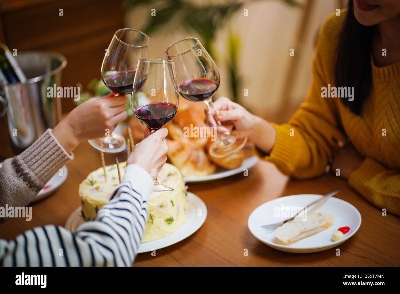 Amis joyeux appréciant la fête d'anniversaire à la maison. Amis asiatiques acclamant boire du vin rouge pour célébrer Noël ou la fête du nouvel an. Banque D'Images