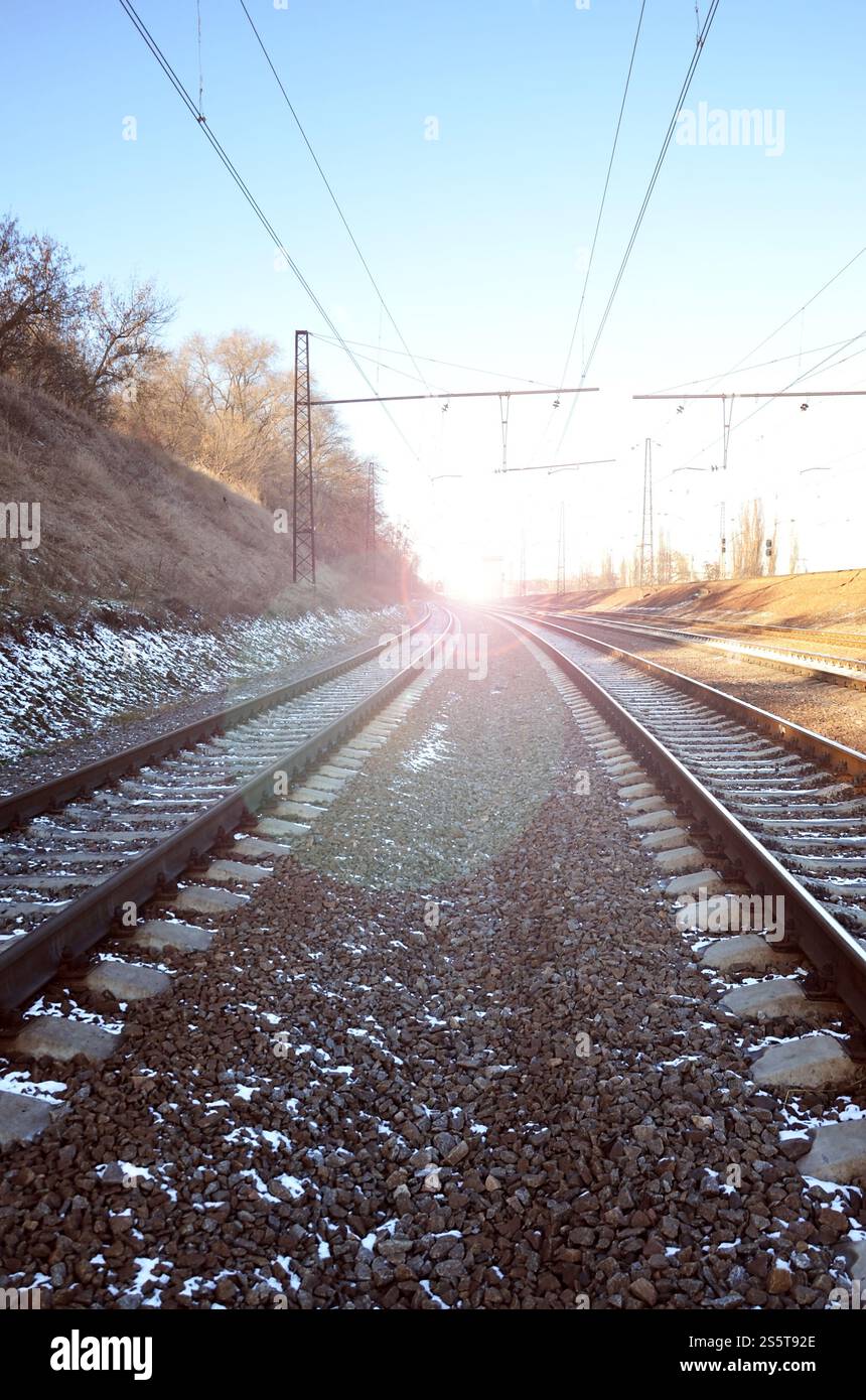 Paysage d'un chemin de fer d'hiver russe enneigé sous la lumière du soleil les rails et les traverses sous la neige de décembre. Chemins de fer russes en détail. Hiver Banque D'Images