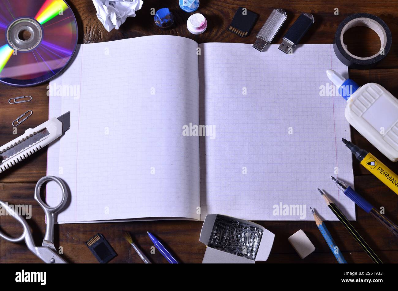 Une nature morte d'école ou de bureau avec un carnet ou un chéquier d'école ouvert et de nombreuses fournitures de bureau. Les fournitures scolaires reposent sur un bois brun Banque D'Images