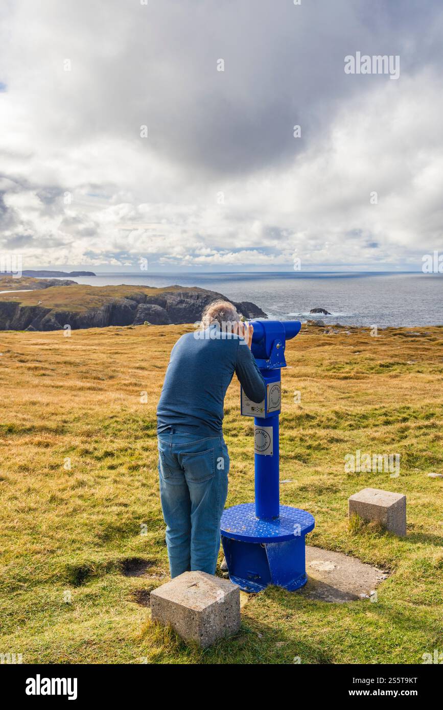 Écosse, Hébrides. Île de Lewis, Aird Uig. Côte accidentée de Gallan Head. Homme utilisant des jumelles. Landes. Banque D'Images