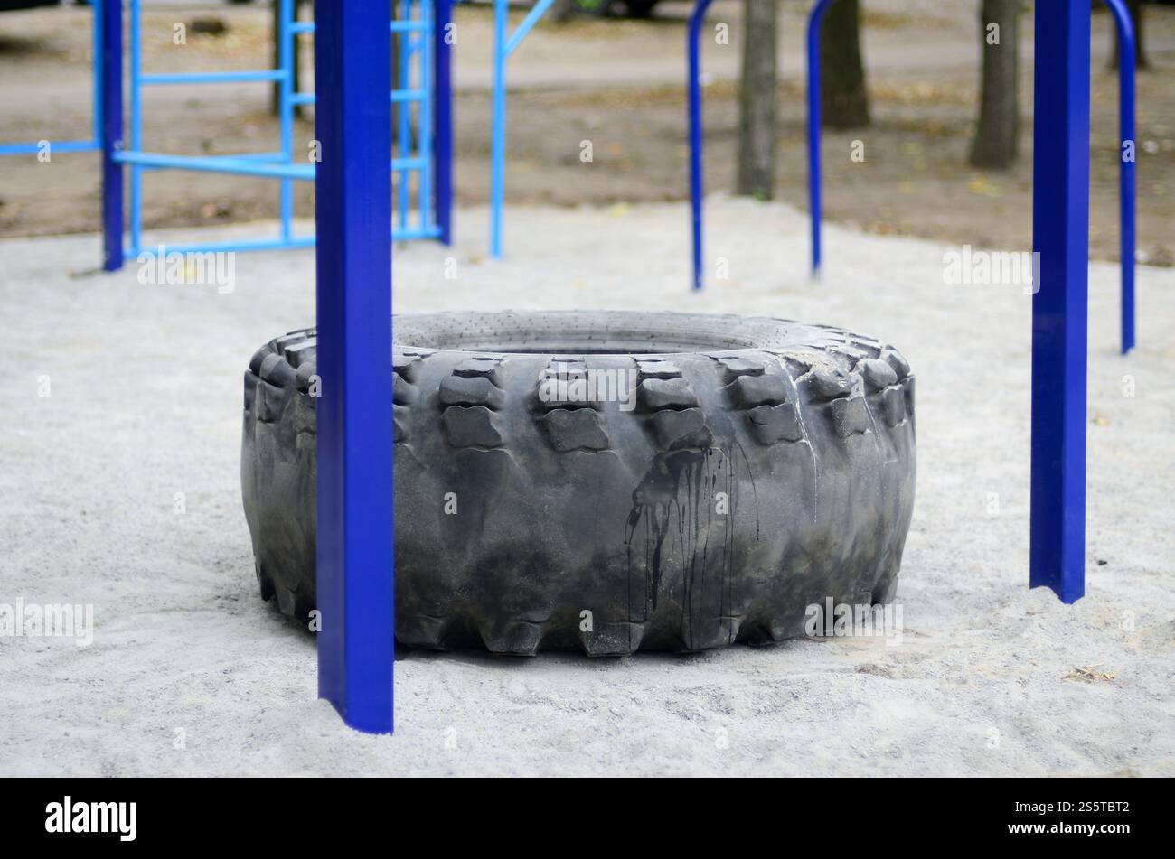 Un grand pneu noir contre un terrain de sport de rue pour l'entraînement athlétique sur piste et terrain et CrossFit. Équipement de gymnastique sportif extérieur. Macro photo Banque D'Images