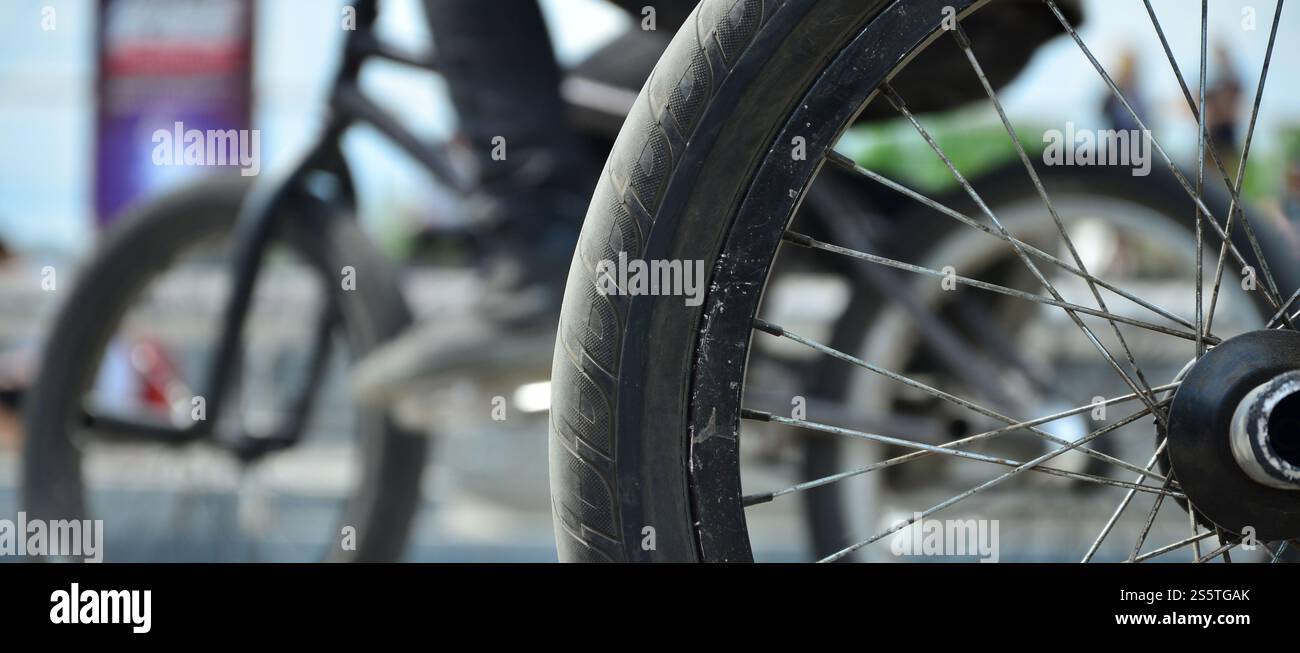 Une roue de vélo BMX dans le contexte d'une rue avec des coureurs cyclistes brouillée. Extreme Sports Concept Banque D'Images Une roue de vélo BMX dans le contexte d'une rue avec des coureurs cyclistes brouillée. Extreme Sports Concept Banque D'Images