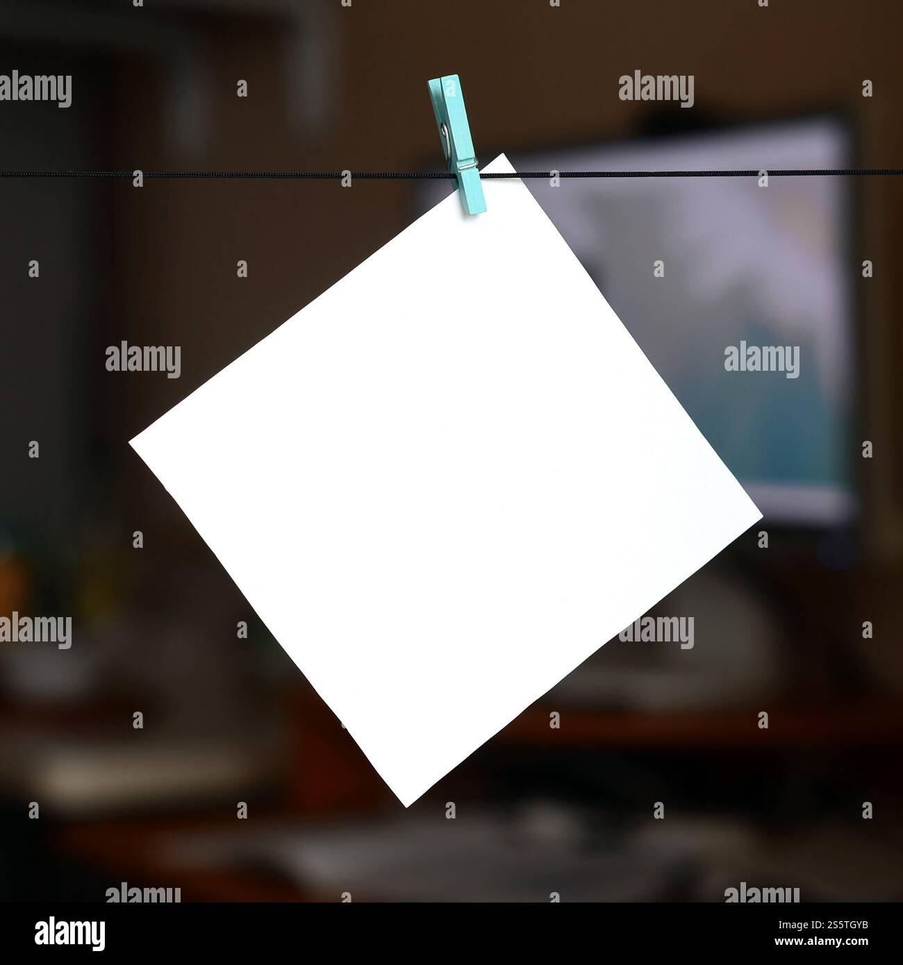 Carte blanche vierge sur corde, fond de bureau sombre. Rappel créatif, petite feuille de papier sur une épinglette en bois, toile de fond de mémo Banque D'Images