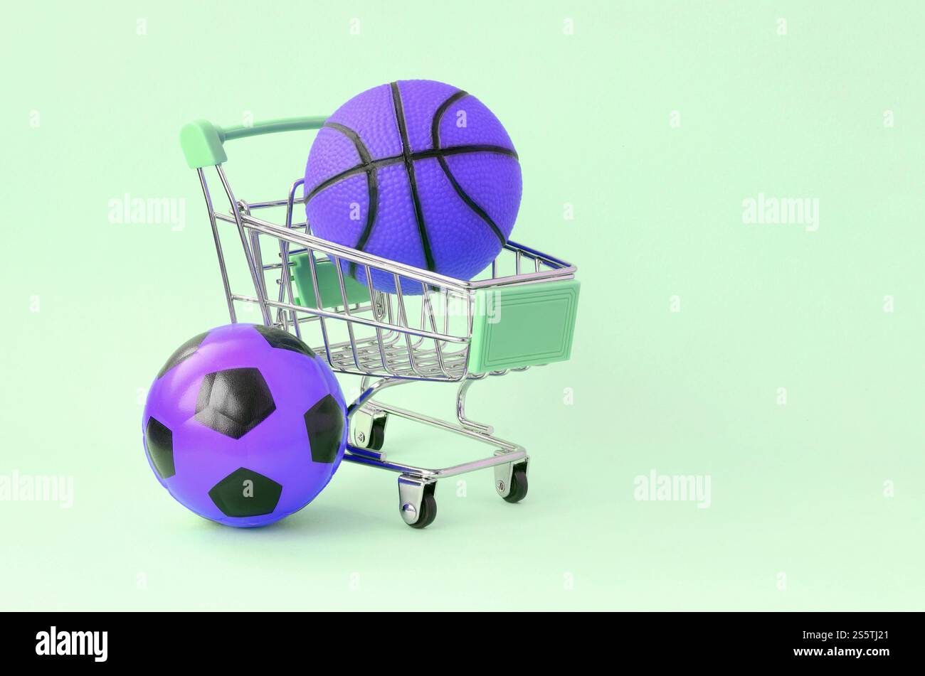Basket-ball violet et ballon de football dans le panier sur turquoise. Le concept de vente d'équipements sportifs, les prévisions pour les matchs sportifs, les sports Banque D'Images