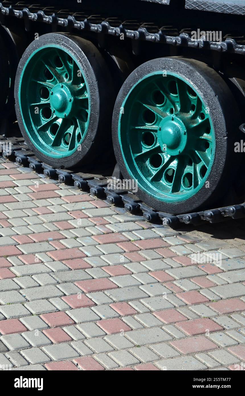 Un véhicule militaire sur chenilles se tient sur un carré de pavés. Photo de chenilles vertes avec des roues en métal que les faire tourner Banque D'Images