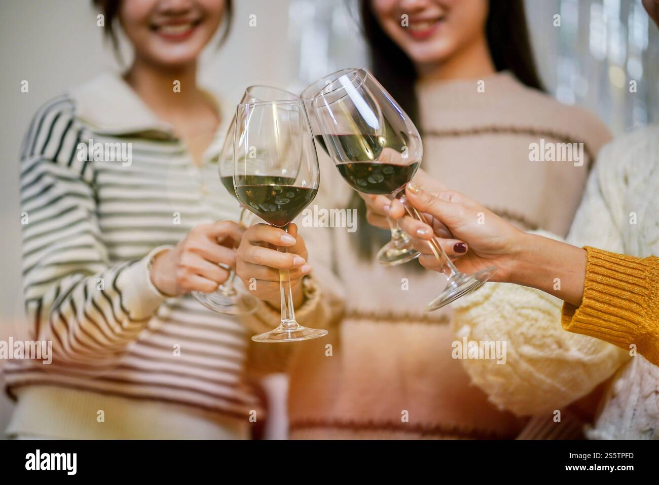 Amis joyeux appréciant la fête d'anniversaire à la maison. Amis asiatiques acclamant boire du vin rouge pour célébrer Noël ou la fête du nouvel an. Banque D'Images