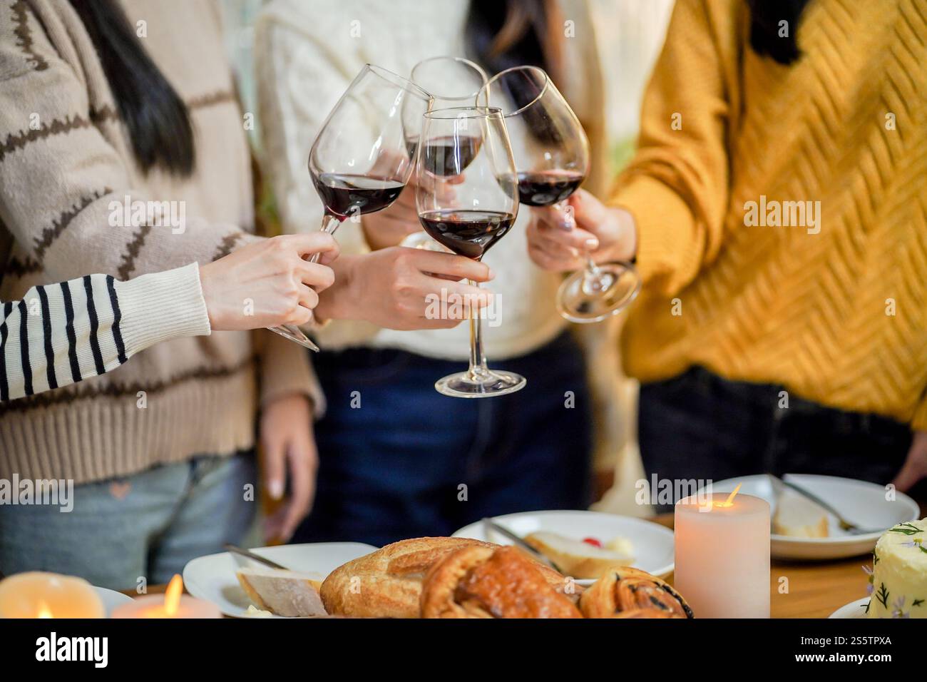 Amis joyeux appréciant la fête d'anniversaire à la maison. Amis asiatiques acclamant boire du vin rouge pour célébrer Noël ou la fête du nouvel an. Banque D'Images