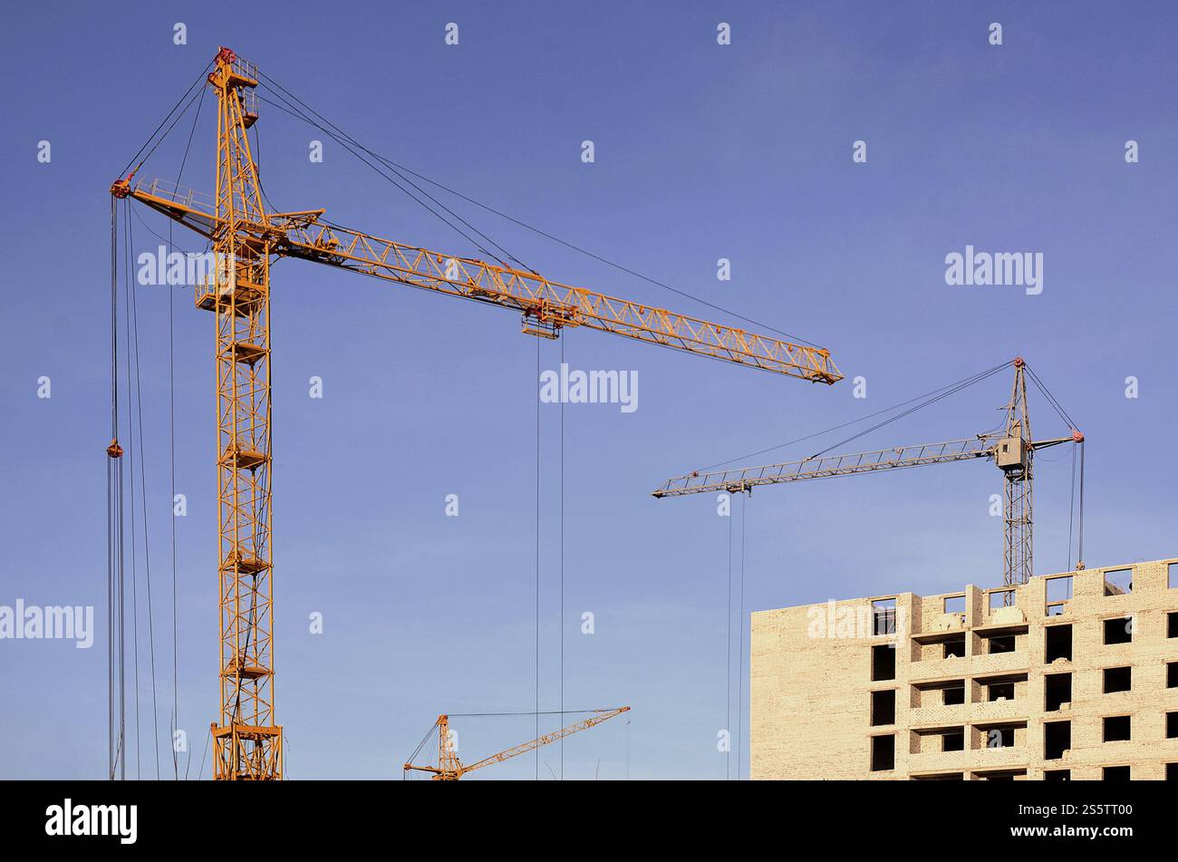 Grues hautes de travail à l'intérieur de l'endroit pour avec des bâtiments hauts en construction contre un ciel bleu clair. Grue et construction progression du travail avec Banque D'Images