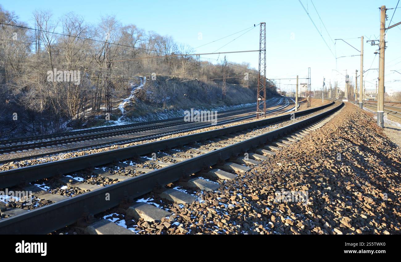 Paysage d'un chemin de fer d'hiver russe enneigé sous la lumière du soleil les rails et les traverses sous la neige de décembre. Chemins de fer russes en détail. Hiver Banque D'Images