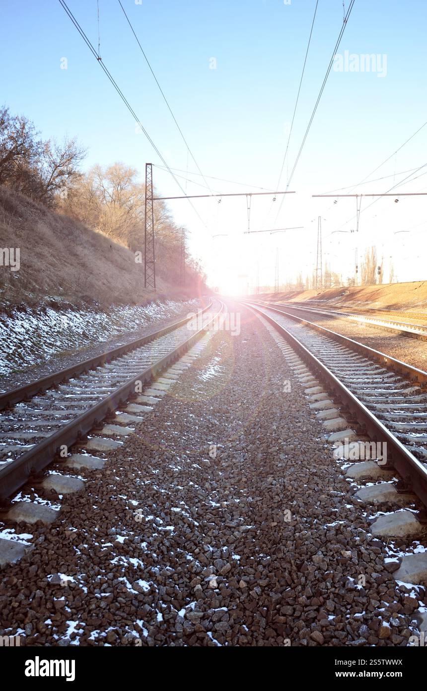 Paysage d'un chemin de fer d'hiver russe enneigé sous la lumière du soleil les rails et les traverses sous la neige de décembre. Chemins de fer russes en détail. Hiver Banque D'Images