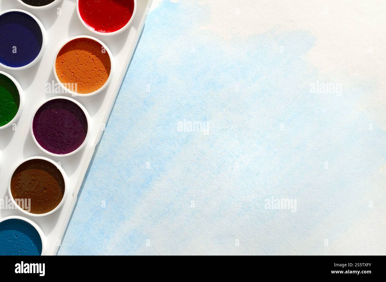 Un nouvel ensemble d'aquarelles repose sur une feuille de papier, qui montre un dessin abstrait d'aquarelle sous la forme de traits bleus. Le concept d'amateur Banque D'Images