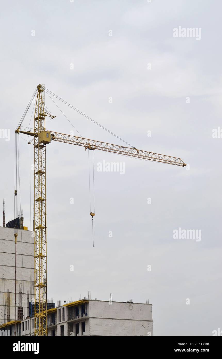 Grues hautes de travail à l'intérieur de l'endroit pour avec des bâtiments hauts en construction contre un ciel bleu clair. Grue et construction progression du travail avec Banque D'Images