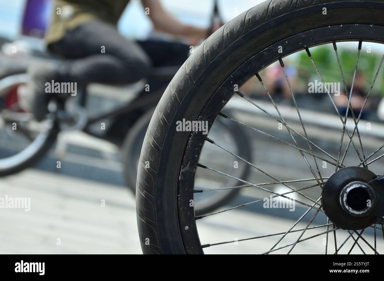 Une roue de vélo BMX dans le contexte d'une rue avec des coureurs cyclistes brouillée. Extreme Sports Concept Banque D'Images Une roue de vélo BMX dans le contexte d'une rue avec des coureurs cyclistes brouillée. Extreme Sports Concept Banque D'Images
