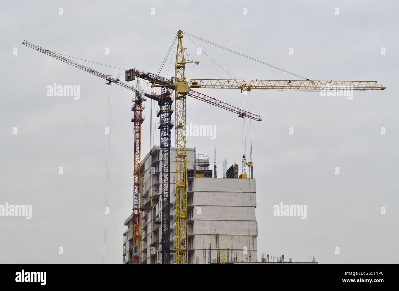 Grues hautes de travail à l'intérieur de l'endroit pour avec des bâtiments hauts en construction contre un ciel bleu clair. Grue et construction progression du travail avec Banque D'Images