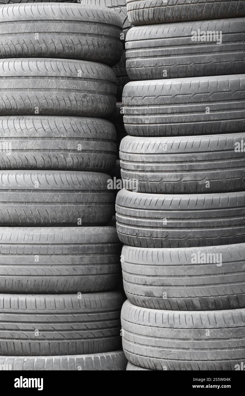 Vieux pneus usagés empilés avec des piles élevées dans le garage secondaire de magasin de pièces de voiture de près. Vieux pneus usagés empilés avec des piles élevées dans des pièces de voiture secondaires Banque D'Images