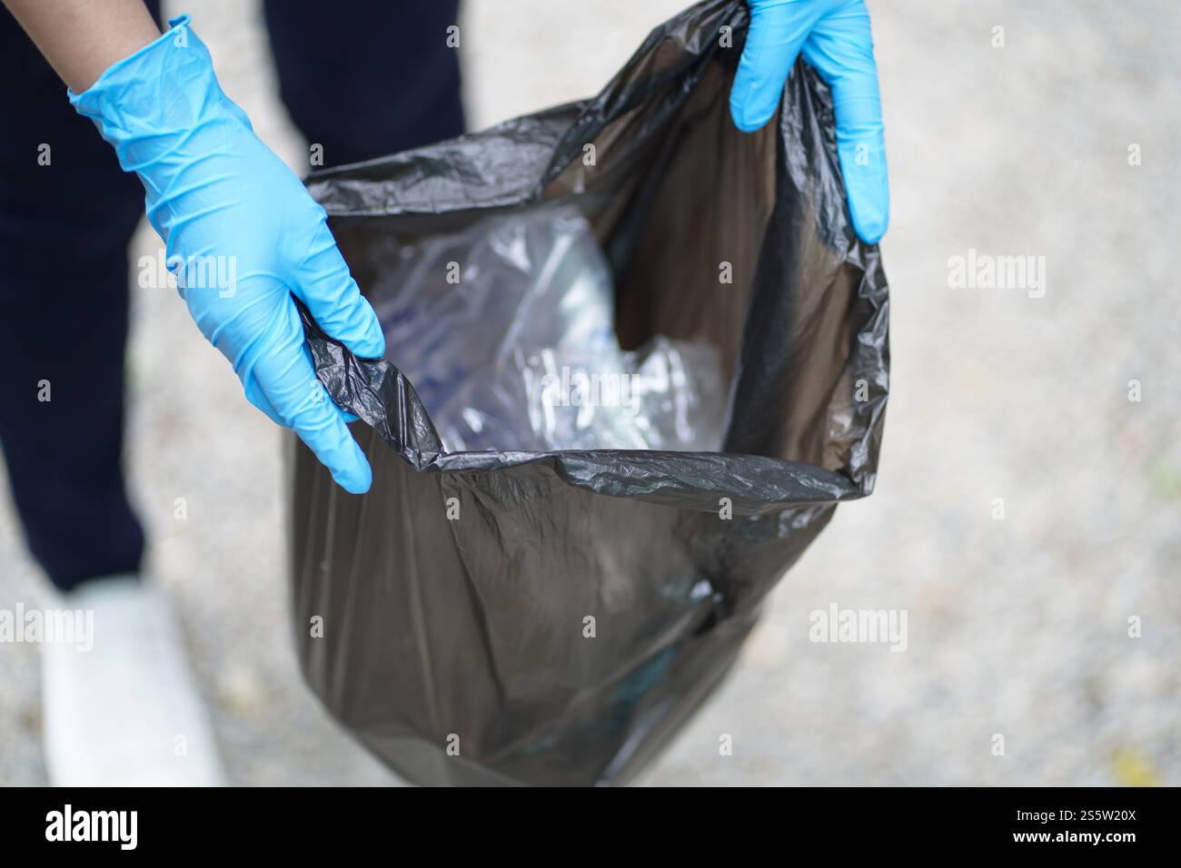 Main de femme de charité bénévole tenant sac noir poubelle et bouteille en plastique poubelle pour le recyclage pour le nettoyage au parc concept de bénévolat réutilisation et Banque D'Images