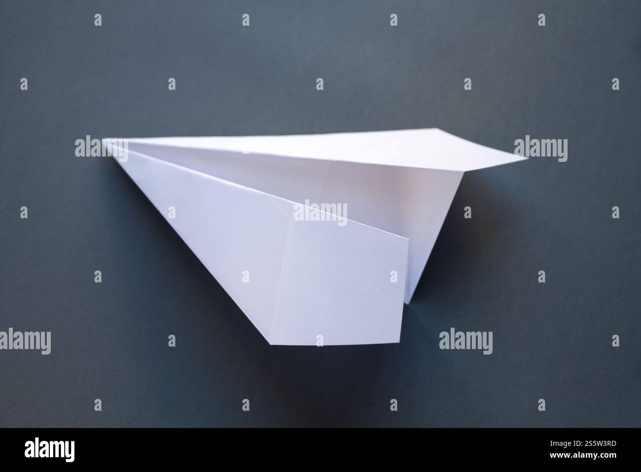 Origami avion en papier blanc isolé sur un fond gris vierge. Origami avion en papier blanc isolé sur un fond gris Banque D'Images