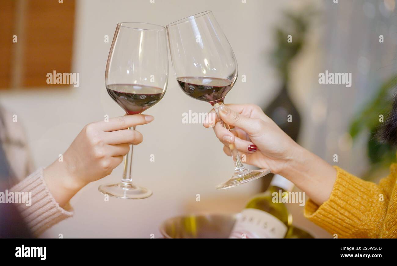 Amis joyeux appréciant la fête d'anniversaire à la maison. Amis asiatiques acclamant boire du vin rouge pour célébrer Noël ou la fête du nouvel an. Banque D'Images