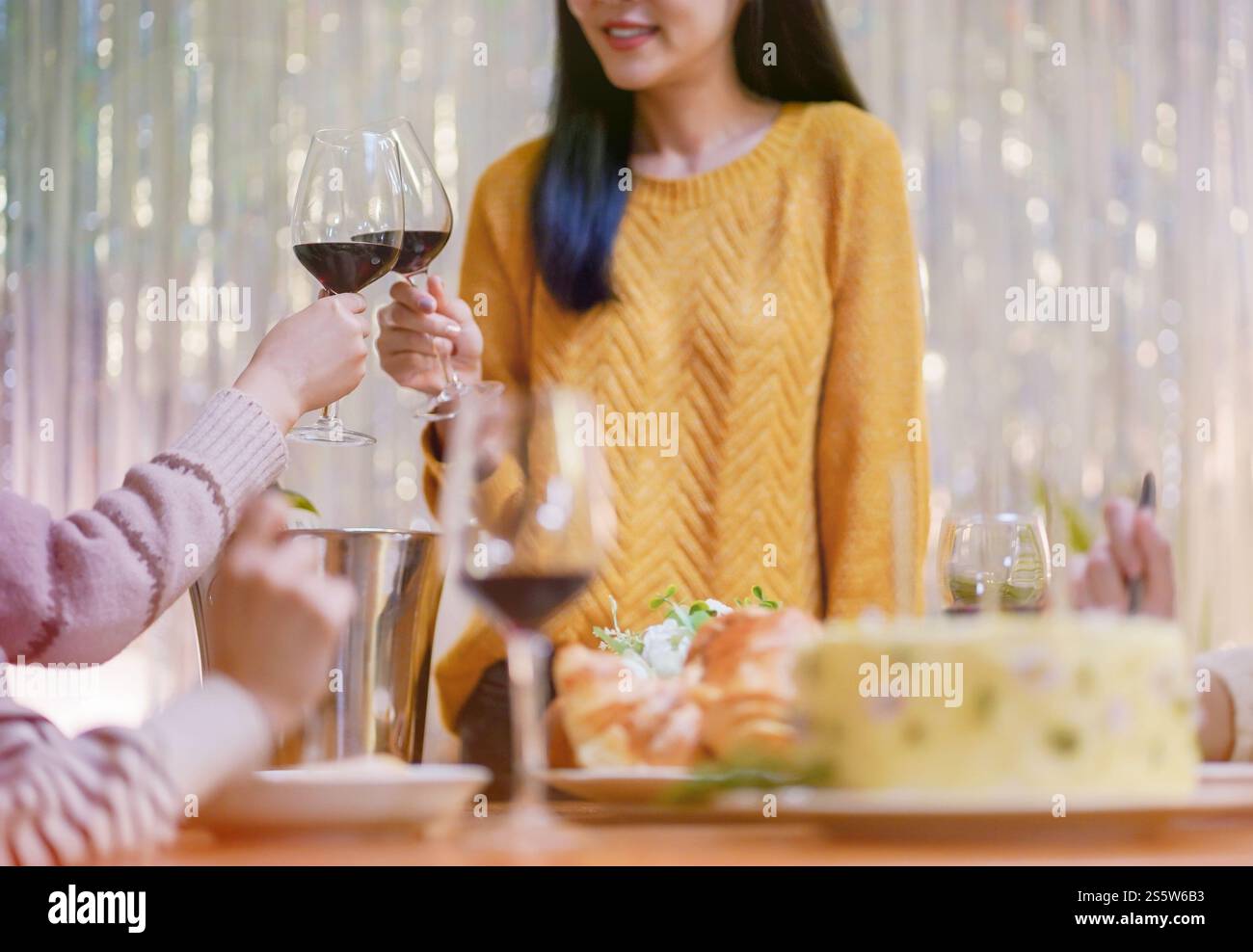 Amis joyeux appréciant la fête d'anniversaire à la maison. Amis asiatiques acclamant boire du vin rouge pour célébrer Noël ou la fête du nouvel an. Banque D'Images