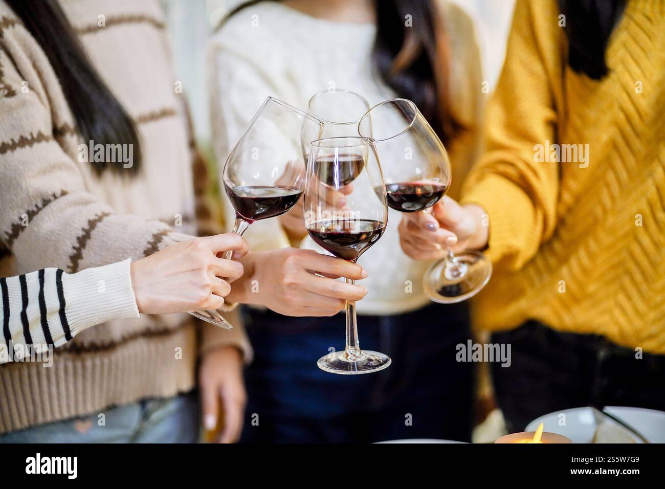 Amis joyeux appréciant la fête d'anniversaire à la maison. Amis asiatiques acclamant boire du vin rouge pour célébrer Noël ou la fête du nouvel an. Banque D'Images