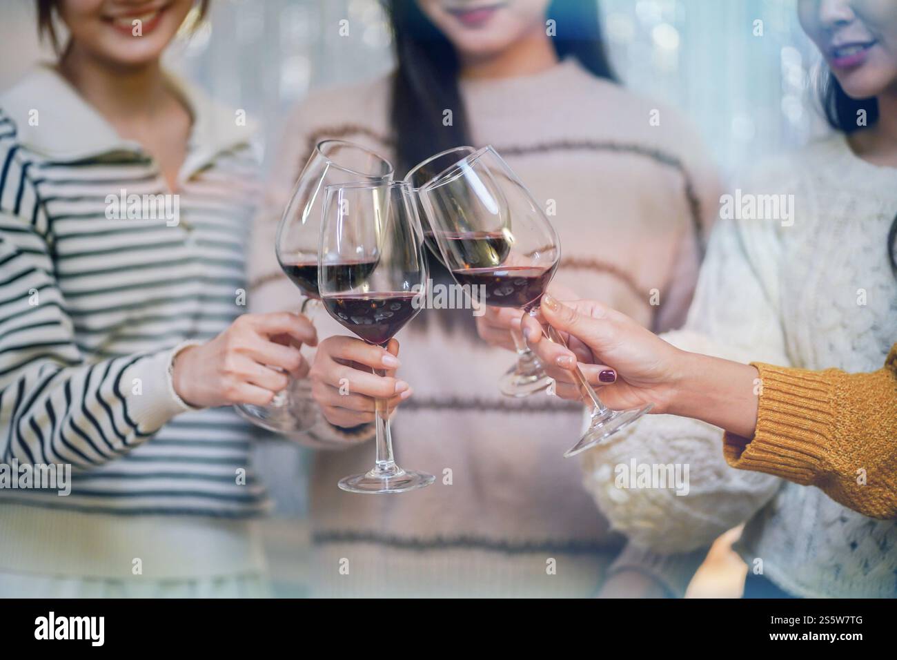 Amis joyeux appréciant la fête d'anniversaire à la maison. Amis asiatiques acclamant boire du vin rouge pour célébrer Noël ou la fête du nouvel an. Banque D'Images
