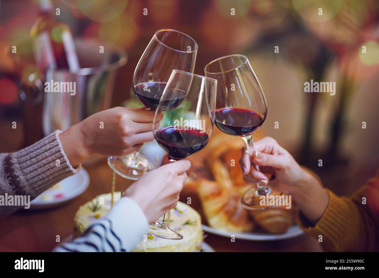 Amis joyeux appréciant la fête d'anniversaire à la maison. Amis asiatiques acclamant boire du vin rouge pour célébrer Noël ou la fête du nouvel an. Banque D'Images