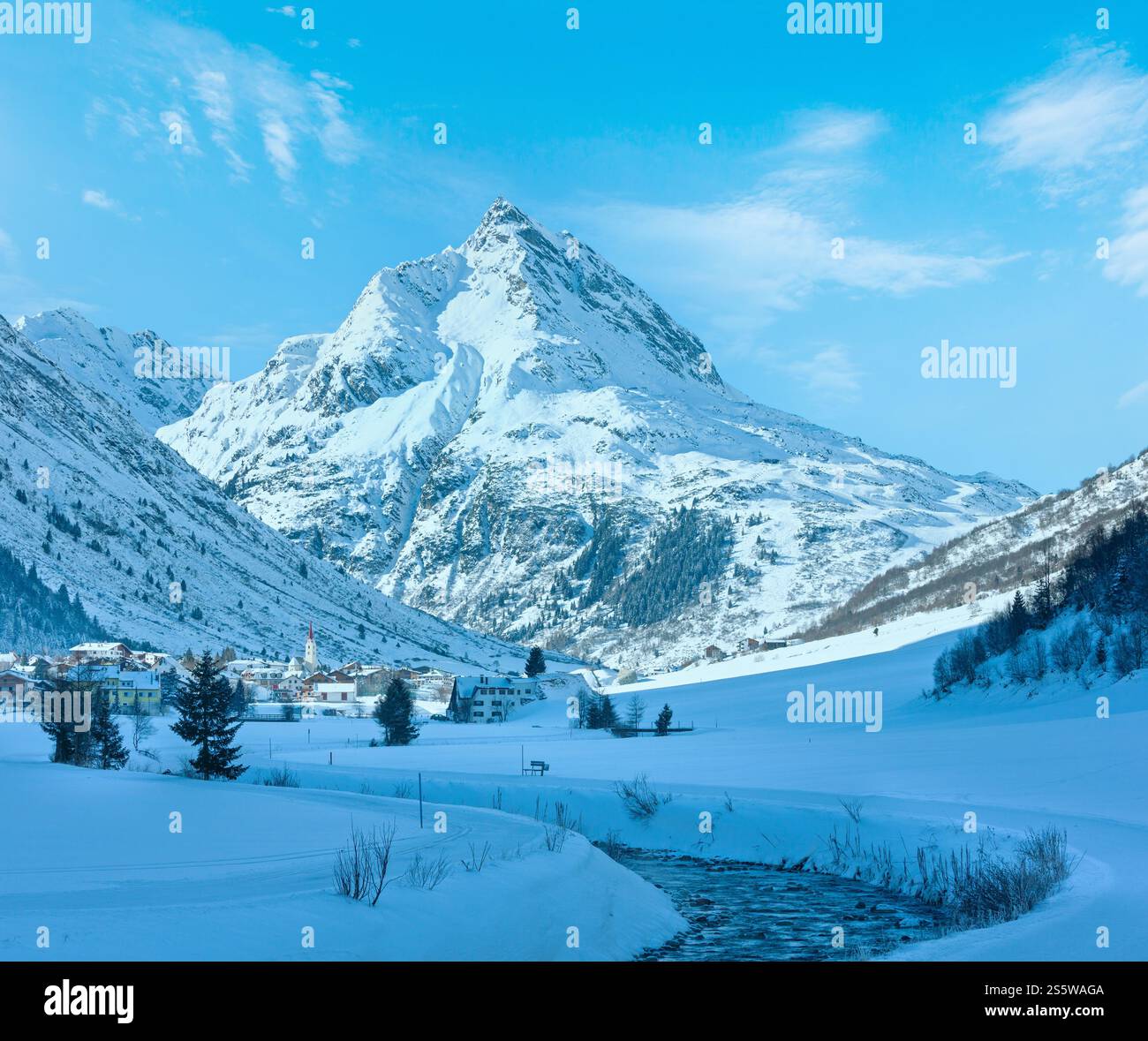 Vue sur les cours d'eau de montagne en hiver et village dans la vallée (Autriche). Banque D'Images