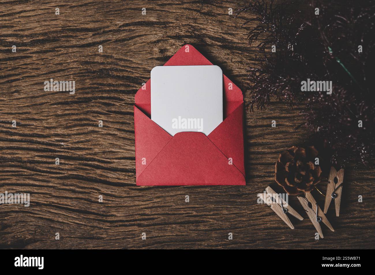Une carte vierge avec une enveloppe rouge et une pince à linge placée sur le fond en bois Banque D'Images