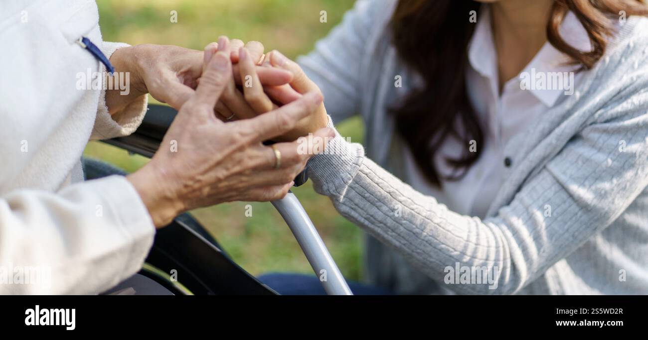 Femme senior asiatique en fauteuil roulant avec fille heureuse. Relation familiale femme retraitée assise sur un fauteuil roulant dans la garde d'âge de parc à la maison de retraite Banque D'Images