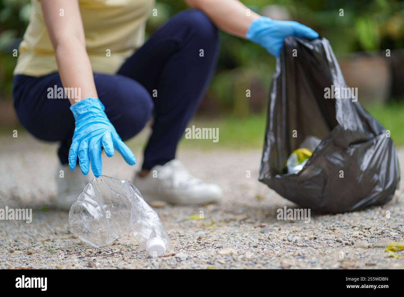 Main de femme de charité bénévole tenant sac noir poubelle et bouteille en plastique poubelle pour le recyclage pour le nettoyage au parc concept de bénévolat réutilisation et Banque D'Images