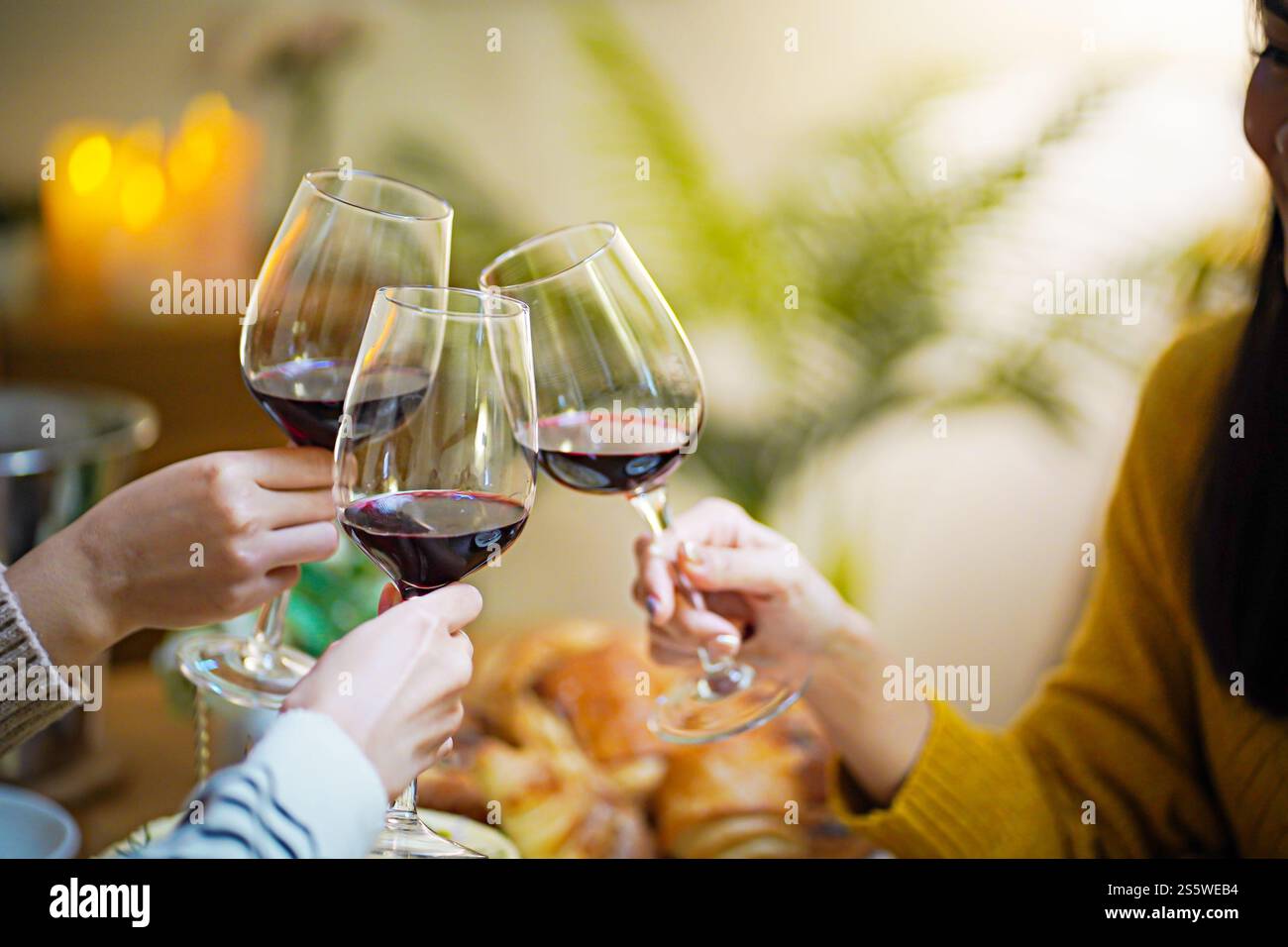 Amis joyeux appréciant la fête d'anniversaire à la maison. Amis asiatiques acclamant boire du vin rouge pour célébrer Noël ou la fête du nouvel an. Banque D'Images