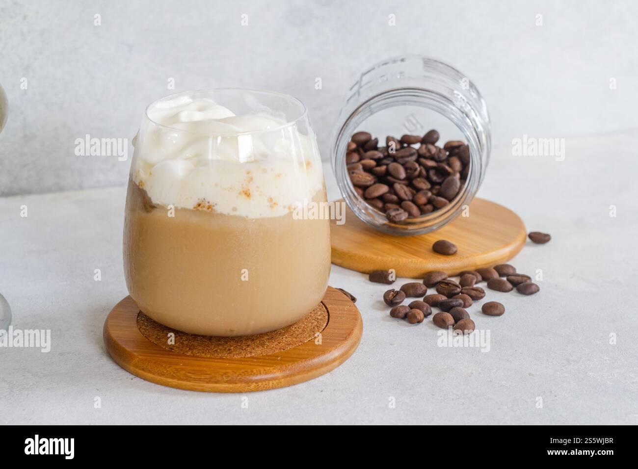 faites couler un espresso froid avec de la mousse de lait froide avec du café moulu brun et des grains de café saupoudrés sur une table blanche Banque D'Images
