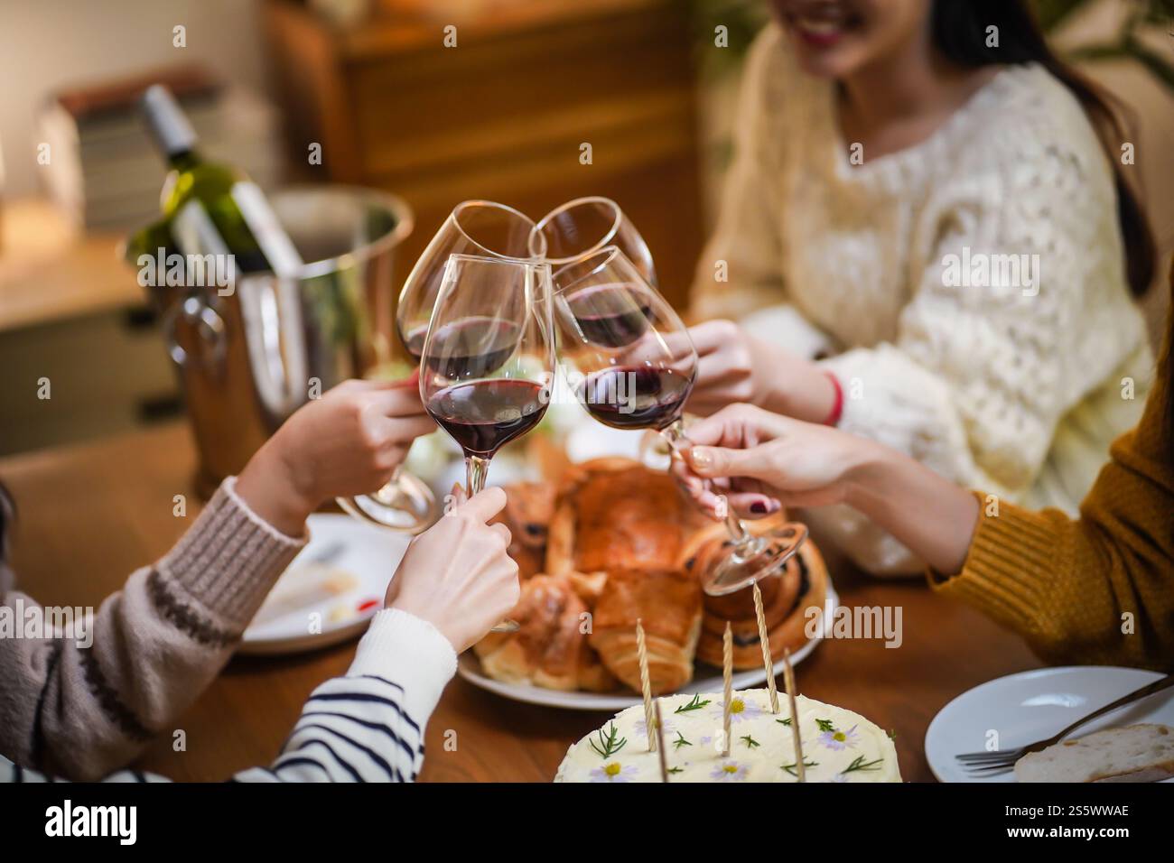 Amis joyeux appréciant la fête d'anniversaire à la maison. Amis asiatiques acclamant boire du vin rouge pour célébrer Noël ou la fête du nouvel an. Banque D'Images