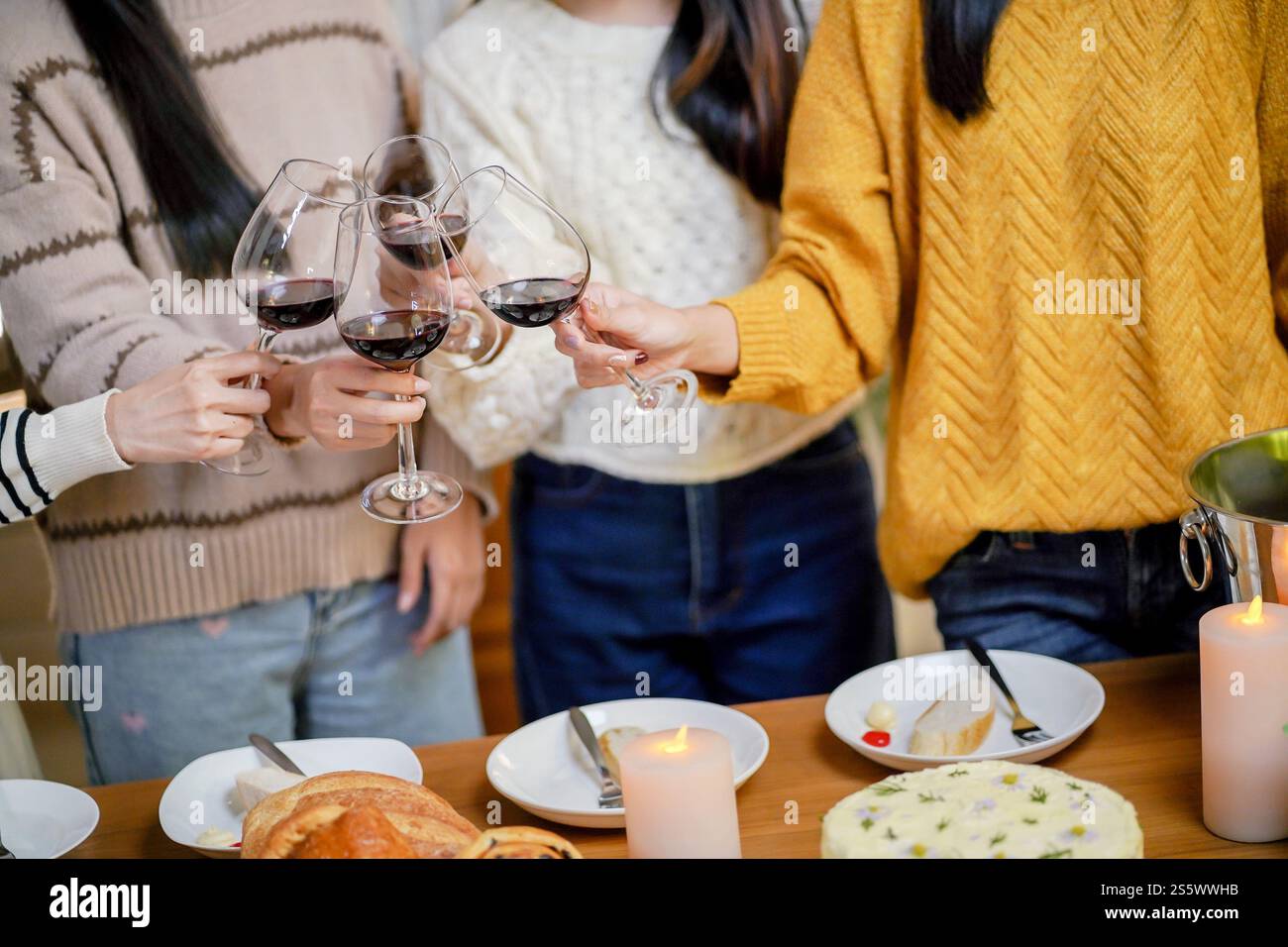 Amis joyeux appréciant la fête d'anniversaire à la maison. Amis asiatiques acclamant boire du vin rouge pour célébrer Noël ou la fête du nouvel an. Banque D'Images