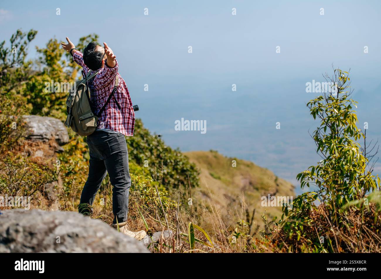 Vue de côté, jeune homme de randonnée asiatique debout et levez-vous les mains avec heureux sur le sommet de la montagne rocheuse, beau paysage en arrière-plan, espace de copie Banque D'Images