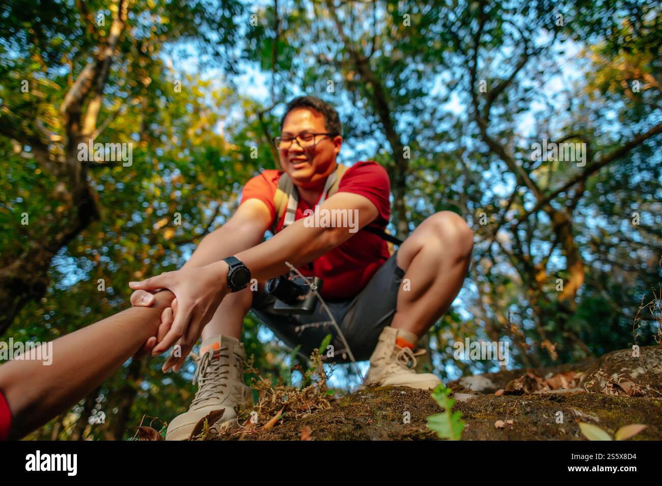 Gros plan et Focus sélectif, jeune homme randonneur sur le dessus tenir quelqu'un de la main aider à grimper pendant le voyage de trekking Banque D'Images
