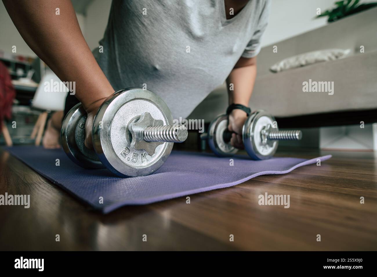 Homme drôle en surpoids faisant la combustion des graisses d'entraînement sur le tapis de sport avec des haltères dans la pose push-up dans le salon, exercice pour un espace de copie sain Banque D'Images