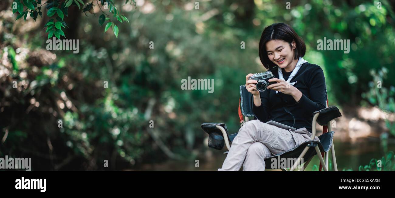Jeune jolie femme utilise un appareil photo numérique prenant une photo belle nature tout en campant dans la forêt avec bonheur, copiez l'espace Banque D'Images