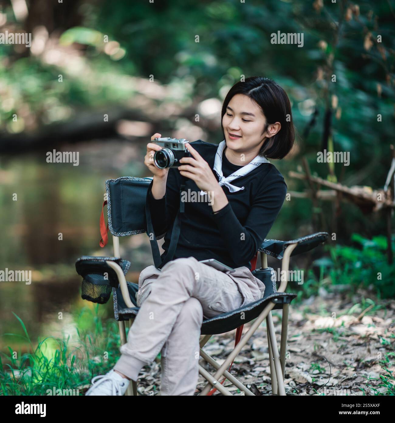 Jeune jolie femme utilise un appareil photo numérique prenant une photo belle nature tout en campant dans la forêt avec bonheur, copiez l'espace Banque D'Images