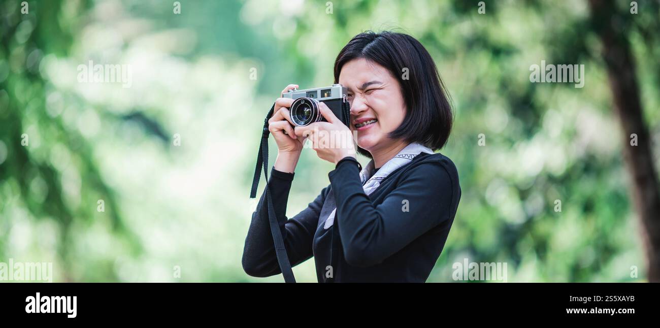 Jeune jolie femme utilise un appareil photo numérique prenant une photo belle nature tout en campant dans la forêt avec bonheur, copiez l'espace Banque D'Images