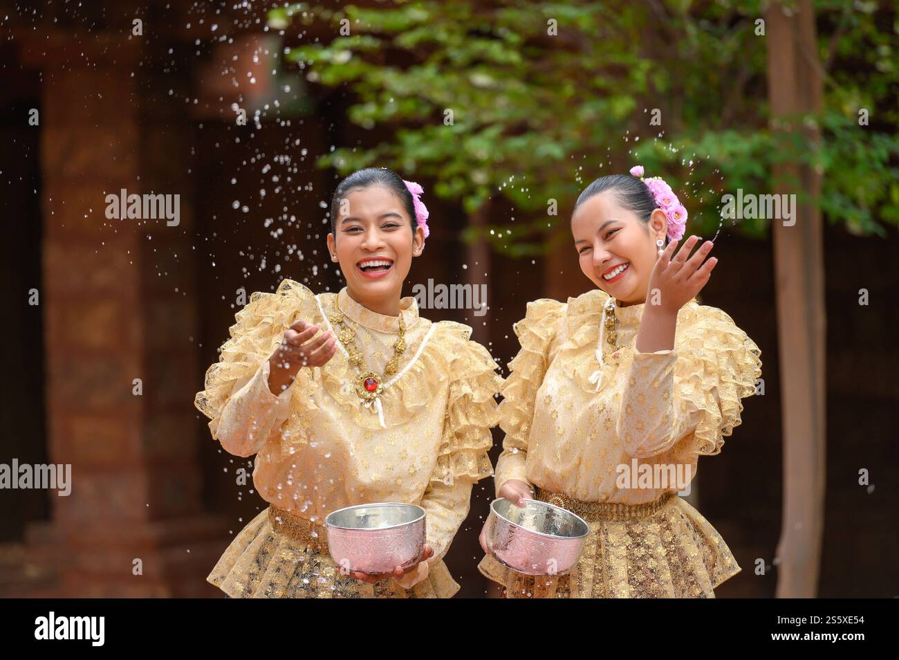 Les jeunes femmes souriantes s'habillent de beaux costumes thaïlandais éclaboussant de l'eau dans les temples et préservant la bonne culture du peuple thaïlandais pendant Songkran Banque D'Images